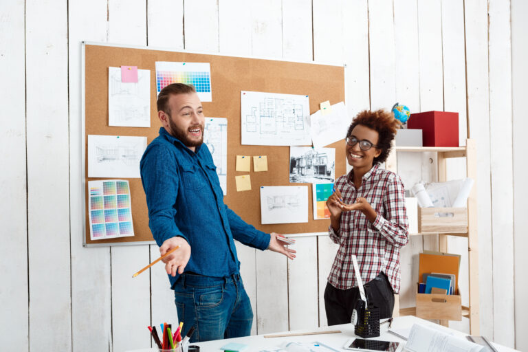 Dois profissionais de design colaborando em uma parede de post-its, um focado em dados de pesquisa e outro em roteiros de texto.